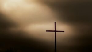 a cross on top of a hill under a cloudy sky