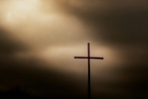 a cross on top of a hill under a cloudy sky